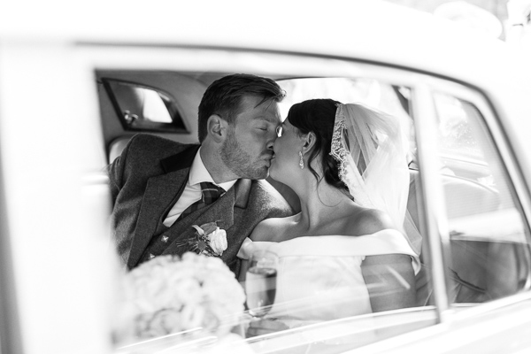 newlyweds kissing in the wedding car in glasgow