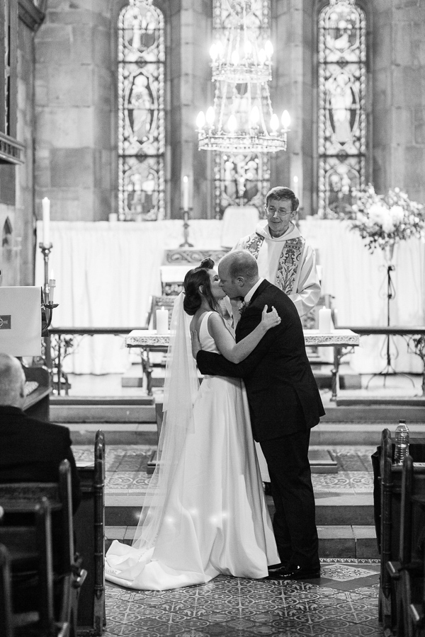 bride and groom kissing at church